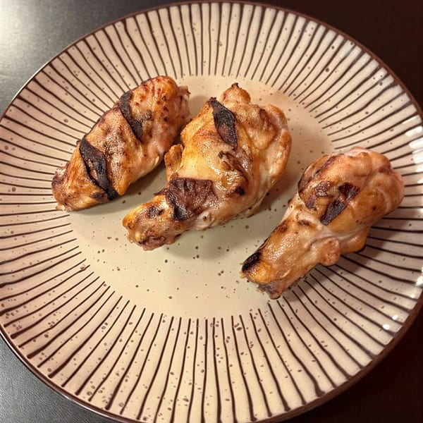 Three grilled chicken wings with char marks on a decorative plate.
